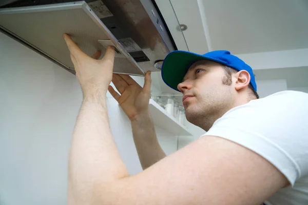 Knappe foreman vaststelling uitlaat kap in de keuken. — Stockfoto