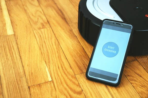 Phone with mobile app to control robotic vacuum cleaner. — Stock Photo, Image