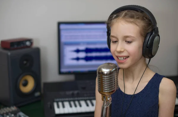 Mała dziewczynka śpiewa piosenkę w domowe studio nagran. — Zdjęcie stockowe