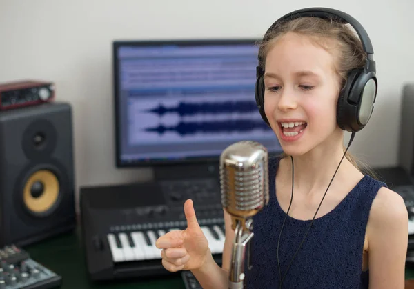 Mała dziewczynka śpiewa piosenkę w domowe studio nagran. — Zdjęcie stockowe