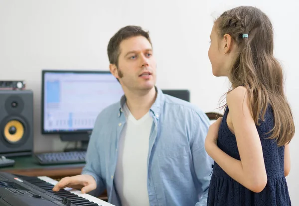 Treinador vocal masculino ensinando a menina a cantar. Focado na menina . — Fotografia de Stock
