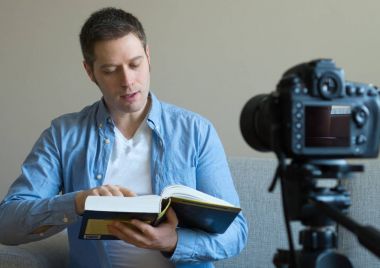 Yakışıklı adam kitap ve eğitim ile ilgili video blog yaparken.