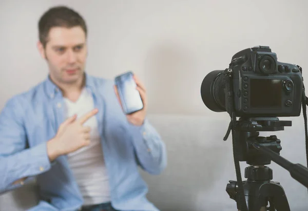 Hombre haciendo video blog sobre teléfonos móviles. Enfoque en cámara . —  Fotos de Stock