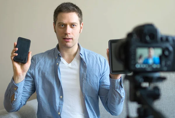 Человек делает видеоблог о разнице между планшетным компьютером и мобильным телефоном . — стоковое фото