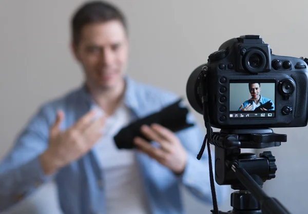 Hombre haciendo video blog sobre lentes de cámara de fotos. Enfoque en cámara . — Foto de Stock