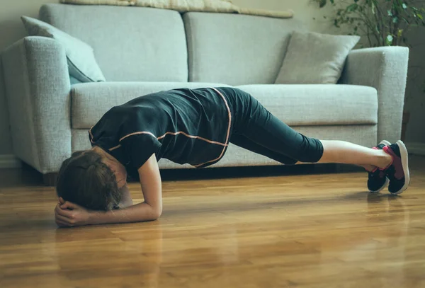 Kleines Mädchen, das zu Hause Übungen für den Bauch macht. Planke. — Stockfoto