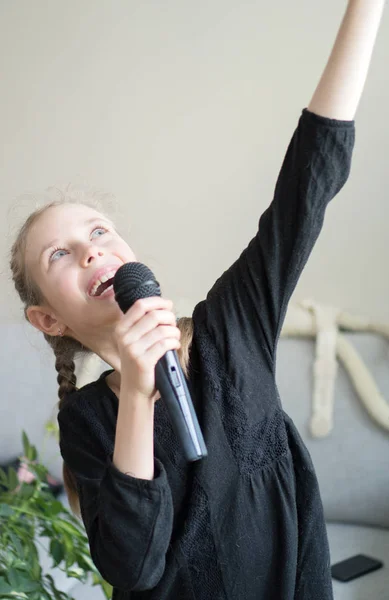 Nettes kleines Mädchen, das zu Hause Karaoke singt. — Stockfoto