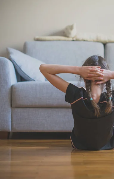 Niña haciendo ejercicios para los abdominales en casa . — Foto de Stock