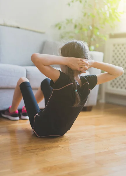 Niña haciendo ejercicios para los abdominales en casa . — Foto de Stock