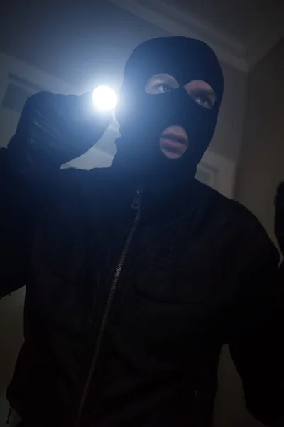 Thief wearing mask with a flashlight in the house. — Stock Photo, Image