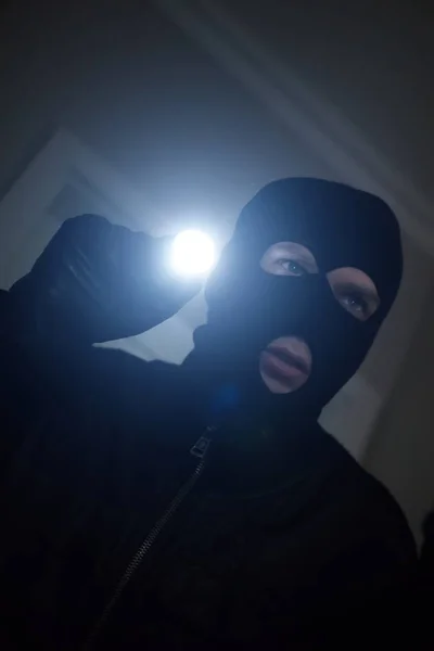 Ladrón usando máscara con una linterna en la casa . — Foto de Stock