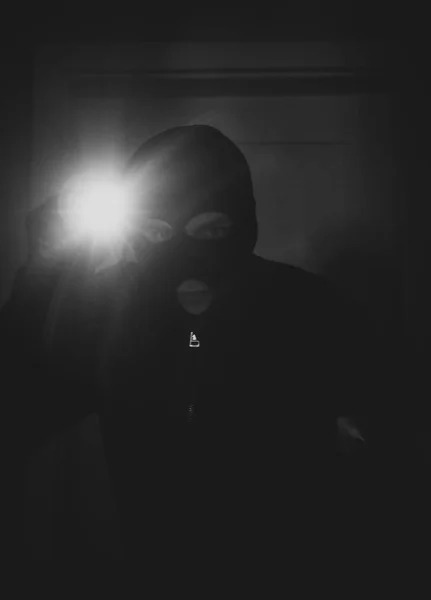 Dieb mit Maske und Taschenlampe im Haus. — Stockfoto