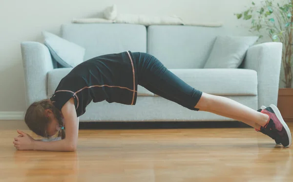 Menina fazendo exercícios para os abdominais em casa. Tábua . — Fotografia de Stock