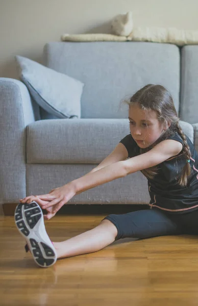 Linda niñita estirándose en casa. Gimnasia en casa . — Foto de Stock