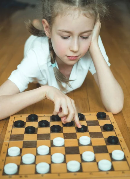 Kleines nettes Mädchen spielt Dame Brettspiel. — Stockfoto
