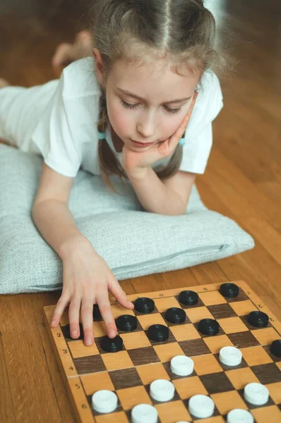 Маленькая милая девочка играет в шашки настольная игра . — стоковое фото