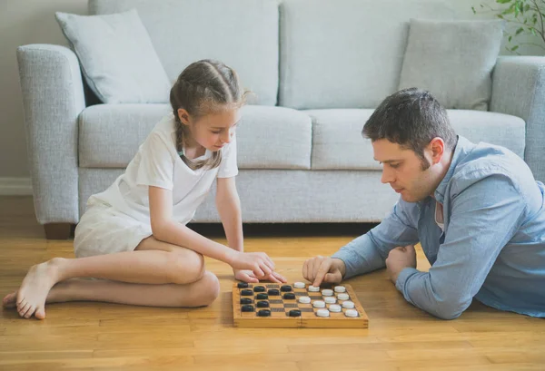 Vader en dochter spelen van dammen bordspel. — Stockfoto