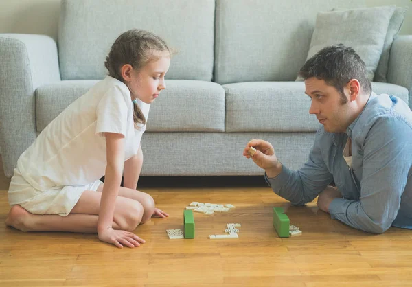 Vater und Tochter spielen zu Hause Dominosteine. — Stockfoto