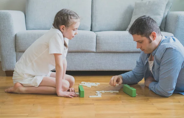 Vater und Tochter spielen zu Hause Dominosteine. — Stockfoto