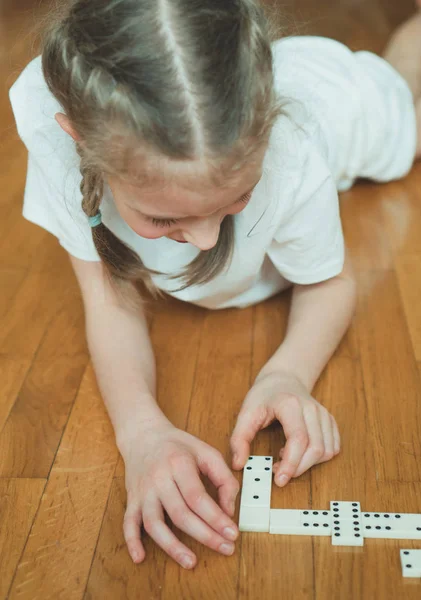 Ładna dziewczynka gra Domino na podłodze. — Zdjęcie stockowe