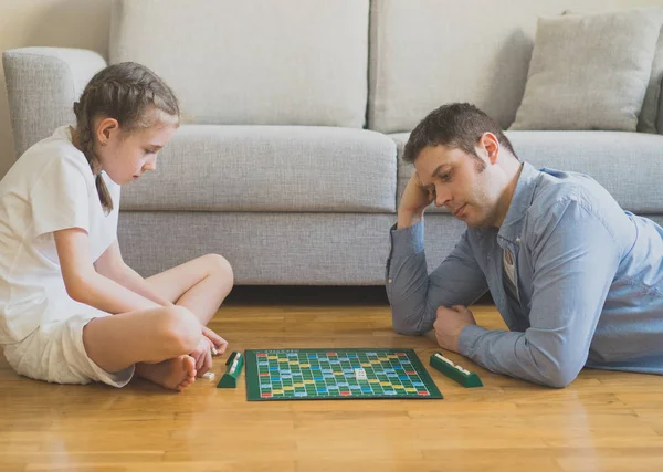 Klein meisje en haar vader spelen scrabble bordspel. — Stockfoto