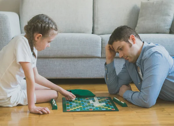 Liten flicka och hennes far spela scrabble brädspel. — Stockfoto