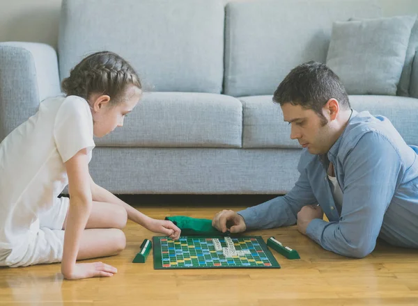 Menina e seu pai jogando scrabble jogo de tabuleiro . — Fotografia de Stock