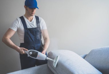 Kanepe ile kuru Buhar temizleyici temizlik Üniformalı erkeklere. Metin için yer.