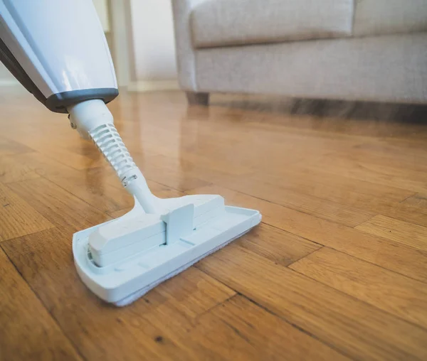 Cleaning the floor with a dry steam cleaner.