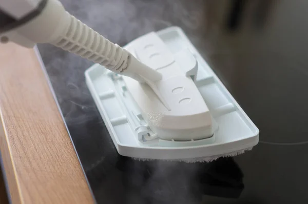 Limpeza de placa de cozinha com um aspirador de vapor . — Fotografia de Stock