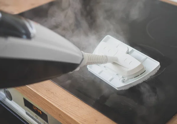 Nettoyage de la plaque de cuisson avec un nettoyeur à vapeur . — Photo