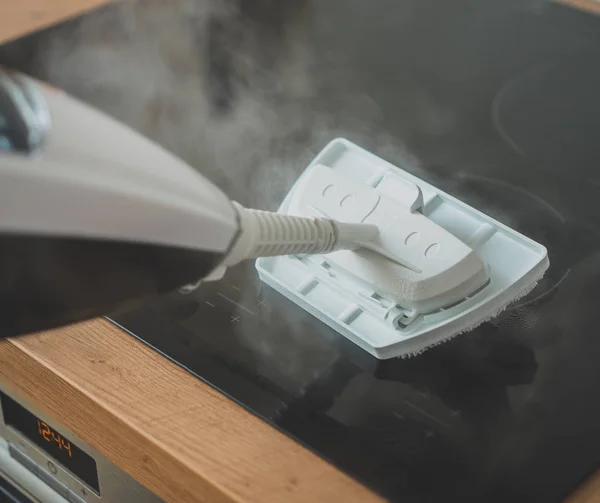 Nettoyage de la plaque de cuisson avec un nettoyeur à vapeur . — Photo