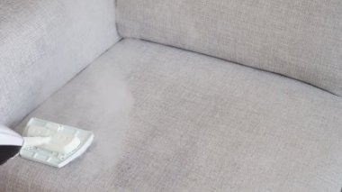 Kumaş koltuk ile bir buhar temizleyici temizlik.