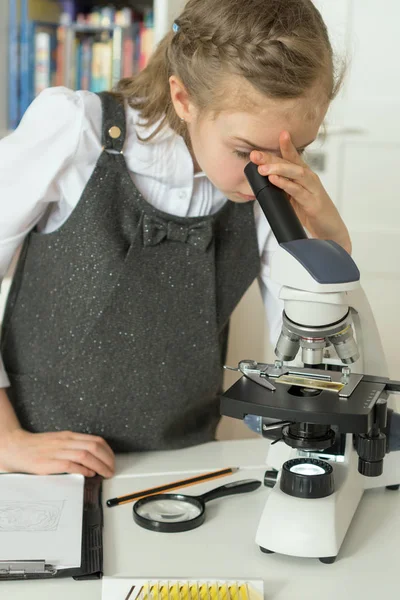 Petite fille en classe de sciences utilisant le microscope . — Photo