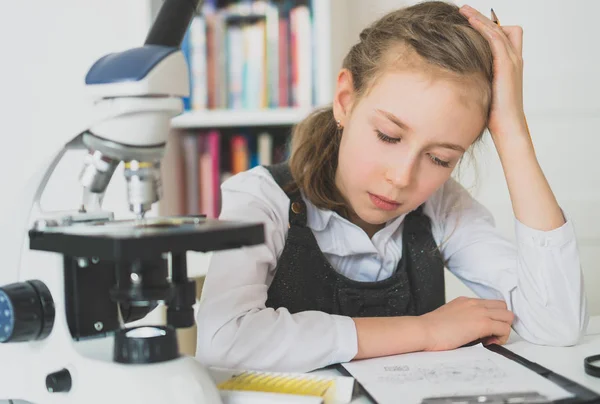 Kleines Mädchen im naturwissenschaftlichen Unterricht mit Mikroskop auf dem Tisch. — Stockfoto