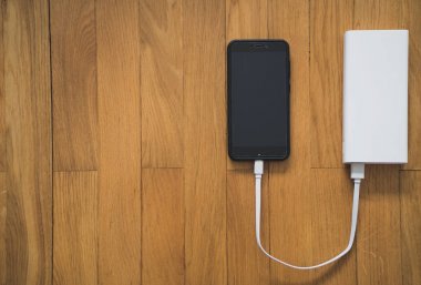 Ahşap yüzey üzerinde beyaz güç banka ile smartphone. Senin metin için yer.