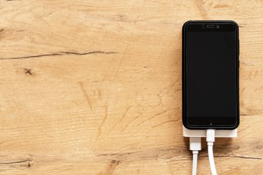 Ahşap yüzey üzerinde beyaz güç banka ile smartphone. Senin metin için yer.
