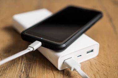 Ahşap yüzey üzerinde beyaz güç banka ile smartphone.