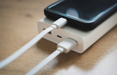 Ahşap yüzey üzerinde beyaz güç banka ile smartphone.
