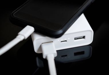 Yansıtılmış yüzeyi beyaz güç banka ile smartphone.