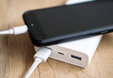 Ahşap yüzey üzerinde beyaz güç banka ile smartphone.