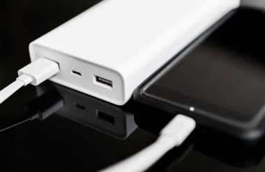 Yansıtılmış yüzeyi beyaz güç banka ile smartphone.