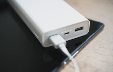 Tablet pc ile beyaz güç kıyısında ahşap yüzey.