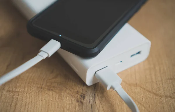 Banco de energía blanco con smartphone en superficie de madera . —  Fotos de Stock