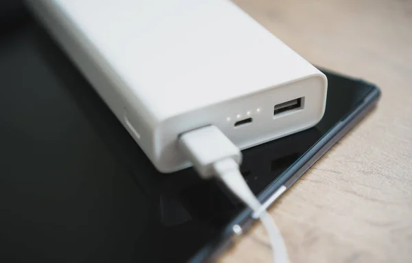 Banco de energía blanco con la PC de la tableta en superficie de madera . —  Fotos de Stock