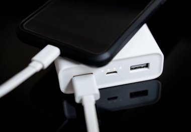 Yansıtılmış yüzeyi beyaz güç banka ile smartphone.