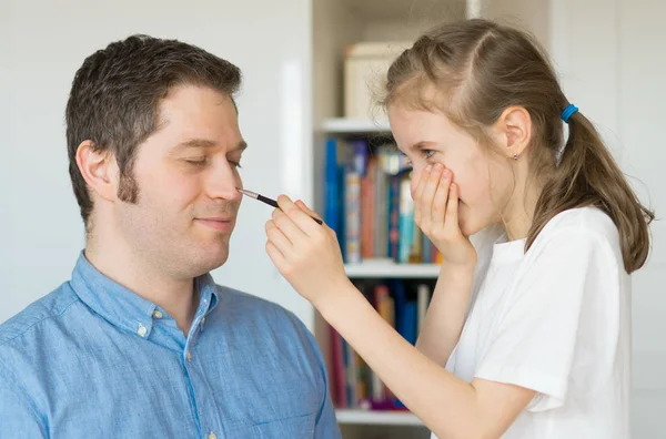 Menina bonito fazendo maquiagem para seu pai . — Fotografia de Stock