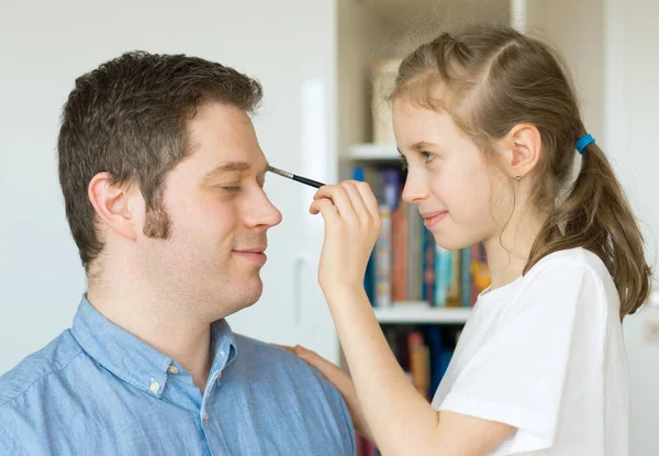 Menina bonito fazendo maquiagem para seu pai . — Fotografia de Stock