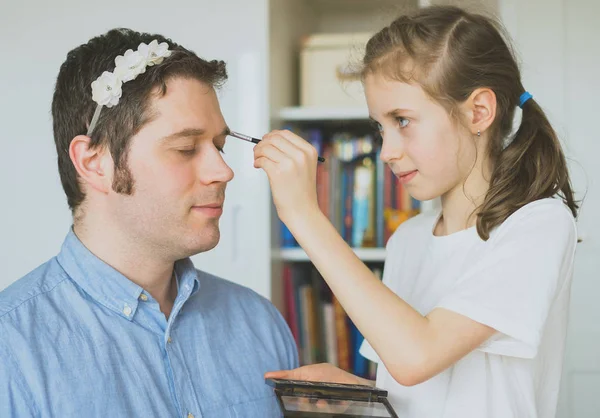 Linda niña haciendo maquillaje a su padre. —  Fotos de Stock