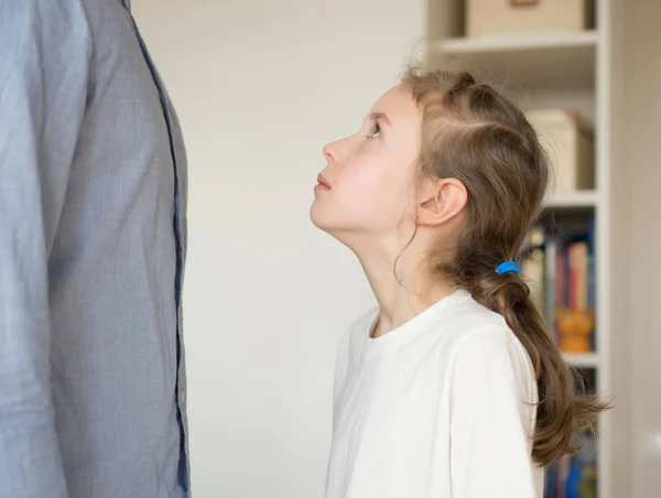 Sorgliga lilla flickan står framför hennes far och tittar på honom. — Stockfoto